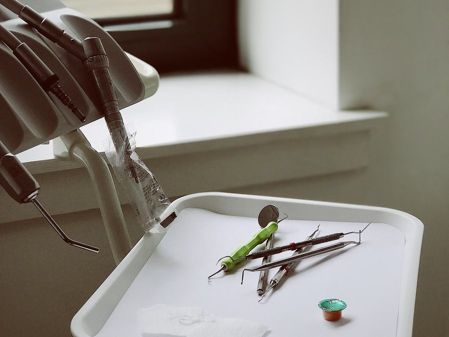Dental instruments on a tray beside a bright clinic window