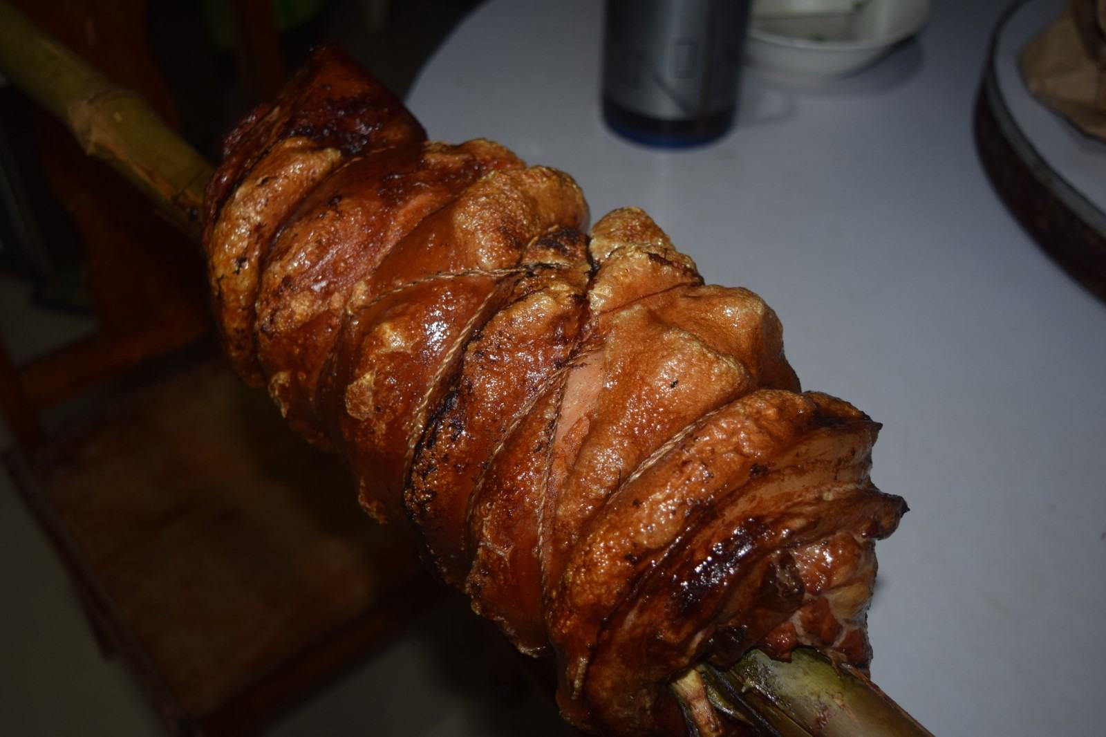 Whole rolled lechon belly roasting over charcoal, golden and crispy